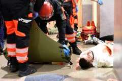 ratownicy medyczni ratujący ranne osoby leżące na podłodze korytarza