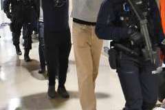 funkcjonariusze policji prowadzący 4 mężczyzn z rękoma założonymi za głowę