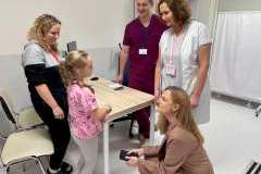 Trzy kobiety, mężczyzna i dziewczynka rozmawiają w sali szpitalnej