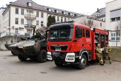 Wóz strażacki i pojazd wojskowy zaparkowane na dziedzińcu szpitala, miejscu wydarzenia