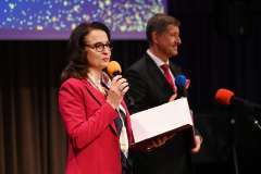 Dwie osoby stoją na scenie przed dużym ekranem