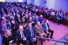 Widownia wypełniona uczestnikami siedzącymi w rzędach podczas uroczystego wydarzenia 