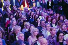 Widownia wypełniona uczestnikami siedzącymi w rzędach podczas uroczystego wydarzenia 