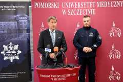 Mężczyzna przemawia przy mównicy PUM, obok stoi policjant.