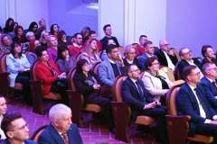 Widownia wypełniona uczestnikami siedzącymi w rzędach podczas uroczystego wydarzenia 