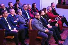 Widownia wypełniona uczestnikami siedzącymi w rzędach podczas uroczystego wydarzenia 