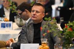 Mężczyzna siedzi przy stoliku i słucha prelegenta