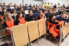 młode kobiety i młodzi mężczyźni siedzący na sali audytoryjnej