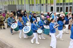 Grupa osób w biało niebieskich strojach gra na bębnach podczas wydarzenia