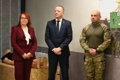 Jedna Kobieta i dwóch mężczyzn stoi podczas konferencji prasowej.