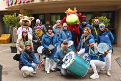 Maskotka pumy i uśmiechnięci młodzi ludzie przed wejściem do szpitala dziecięcego