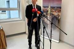 Mężczyzna w garniturze stoi i mówi przez mikrofon, w tle baner Pomorskiego Uniwersytetu Medycznego