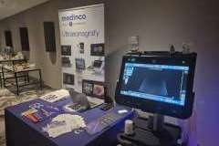 stolik wystawowy z ulotkami, obok stoi ultrasonograf