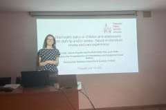 Kobieta stojąca w sali wykładowej przed ekranem rzutnika z wyświetloną prezentacją