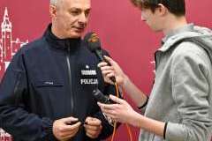 Policjant udziela wywiadu młodemu reporterowi przy mikrofonie