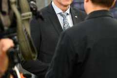 Mężczyzna w garniturze rozmawia z dziennikarzami podczas briefingu