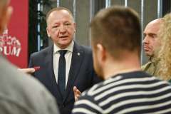 Mężczyzna w garniturze rozmawia z dziennikarzami podczas briefingu