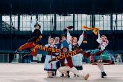 Cztery uśmiechnięte panie i trzech panów w strojach ludowych stoją przed stadionem 