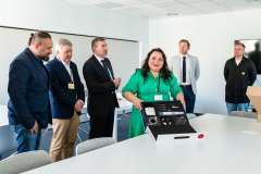 Kobieta wśród zgromadzonych mężczyzn dokonuje pokazu skanera