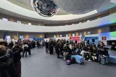 młodzi ludzie w sali ze stoiskami promocyjnymi uczelni