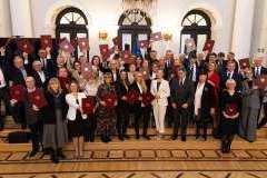 duża grupa osób stojących w eleganckich wnętrzach, niektórzy trzymają w rękach dyplomy