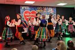 Mężczyźni i kobiety w strojach ludowych występują na scenie podczas wydarzenia WOŚP.