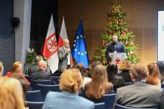 uczestnicy konferencji słuchają dwóch mężczyzn stojących i rozmawiających na scenie