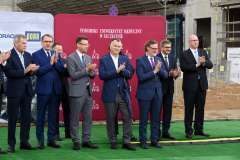 stoi grupa osób i biją brawo, w tle ścianka reklamowa z logotypami 