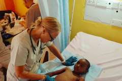 medyk pochyla się nad dzieckiem leżącym na łóżku szpitalnym