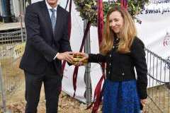 Kobieta i mężczyzna stoją przed terenem budowy, za nimi wisi wiecha