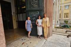 Trzy kobiety stoją przed tablicą z logo Sapienza University of Rome.