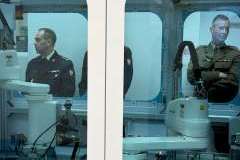 Grupa dorosłych osób stoi w pomieszczeniu i ogląda otoczenie. zdjęcie zrobione przez szybę