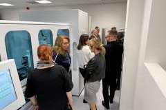 Grupa dorosłych osób stoi w pomieszczeniu i ogląda otoczenie