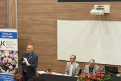 prelegent w sali konferencyjnej wygłasza wykład, na ścianie ekran z prezentacją