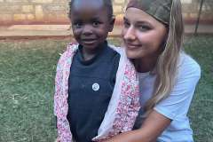 młoda kobieta kuca na trawie i przytula małą dziewczynkę