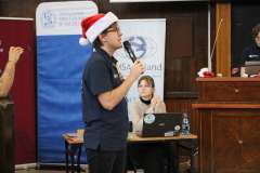 młody mężczyzna w czapce mikołaja mówi przez mikrofon 