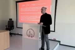 Mężczyzna stoi przy mównicy z logo PUM i przemawia na tle slajdu prezentacji