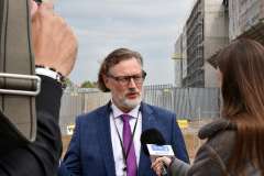 mężczyzna udzielający wywiadu, w tle budowa