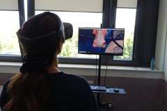 Młoda osoba w sali warsztatowej z nałożonymi okularami VR, na ekranie przed obrazy medyczne