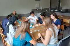 Młode osoby siedzące przy stole wykonujące ćwiczenia szycia na zwierzęcej skórze