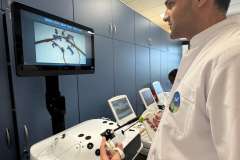 Młody mężczyzna w fartuchu lekarskim w trakcie ćwiczeń laparoskopem