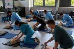 Grupa młodych osób podczas warsztatów, pochylonych nad fantomami do symulacji RKO