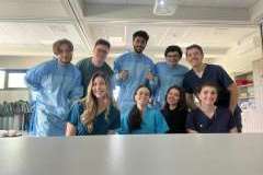 Grupa młodych, uśmiechniętych ludzi w sali warsztatowej. Część stoi, część kuca