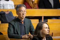 Mężczyzna w okularach i kobieta siedzą w auli wykładowej, czekając na spotkanie