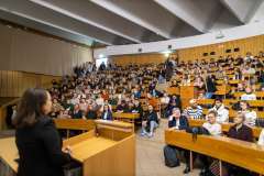 Pełna aula wykładowa z liczną publicznością oraz prelegentką stojącą przy mównicy