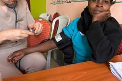 mężczyzna w uniformie medycznym podczas badania kobiety która siedzi obok niego 