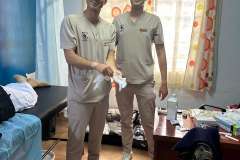 dwóch mężczyzn w uniformach medycznych stoi na środku pokoju zabiegowego, uśmiechają się do aparatu