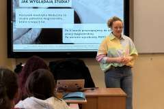 kobieta stoi obok ekranu z prezentacją zatytułowaną „Jak wyglądają studia?” 