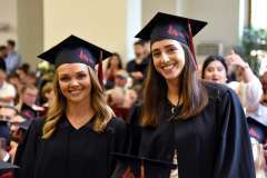 Uroczystość absolutoryjna. Dwie uśmiechnięte studentki w togach i biretkach