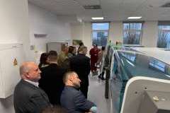 Grupa dorosłych osób stoi w pomieszczeniu i ogląda otoczenie